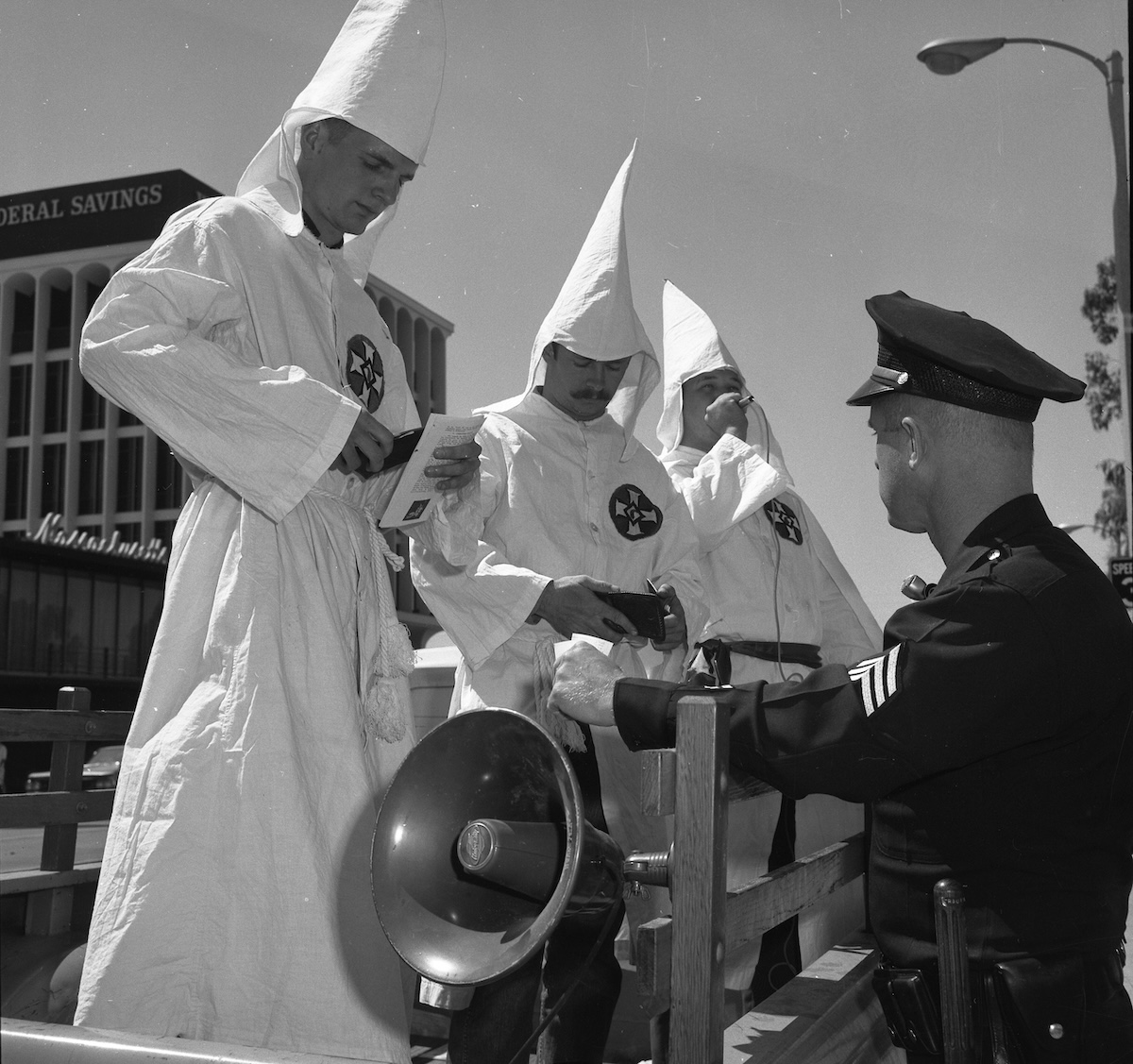 A police officer checks the ID of three members of the Ku Klux Klan in Panorama City, California, 18 September 1966. University of California, Los Angeles. Library. Department of Special Collections (CC BY 4.0). A police officer checks the ID of three members of the Ku Klux Klan in Panorama City, California, 18 September 1966. University of California, Los Angeles. Library. Department of Special Collections (CC BY 4.0).